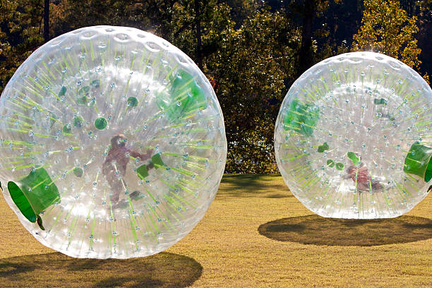 Kids Rolling Inside Large Plastic Balls Kids push along from inside two separate plastic balls (zorbing) zorbing stock pictures, royalty-free photos & images
