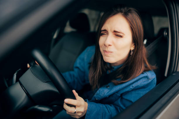 mujer entrecerrando los ojos y conduciendo sin tener la visibilidad adecuada - entrecerrar los ojos fotografías e imágenes de stock