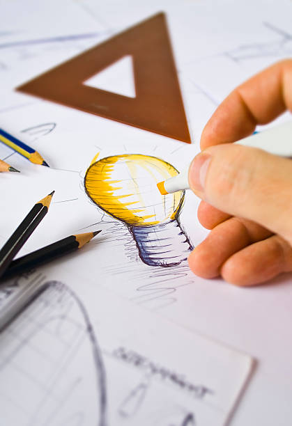 Designer drawing and coloring a light bulb A designer drawing sketches product designer photos stock pictures, royalty-free photos & images