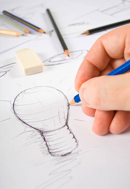 istock Artist's hands drawing a pencil sketch of a lightbulb 137164654