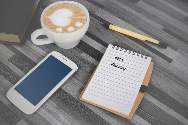 istock 401 K Planning text on Book note ,smart phone and coffee on office table . 1371660556