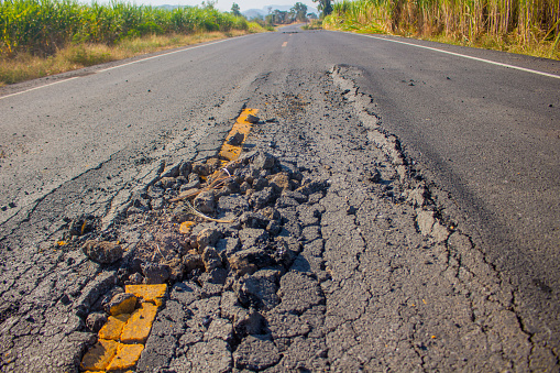 Damaged roads in rural areas. Damaged asphalt. It's dangerous to drive on this road.