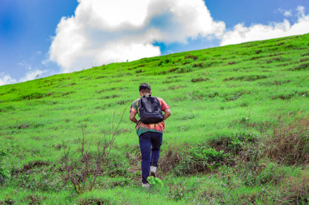 istock Young man climbing a hill with blue sky , back traveler climbing a hill, back guy hiking 1371669092