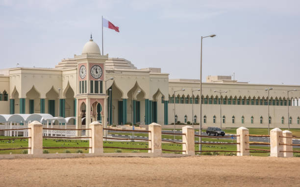 Qatar national flag flying over Amiri Diwan Parliament Building and clock tower stock photo