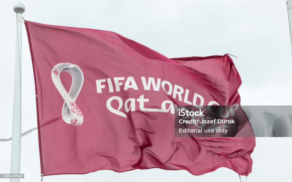 Maroon Fifa World Cup Qatar 2022 flag flying in the sky above Doha Doha, Qatar - January 15th 2022: Maroon Fifa World Cup Qatar 2022 flag flying in the sky above Doha International Soccer Event Stock Photo