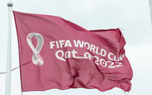 Maroon Fifa World Cup Qatar 2022 flag flying in the sky above Doha stock photo