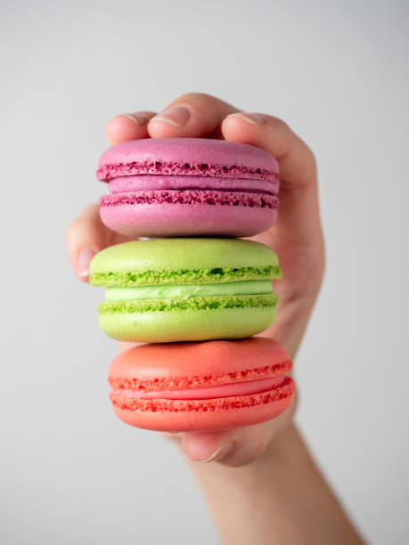 istock Close-up of a woman's hand holding three multi-colored macaroons. Front view, vertical photo 1371679600