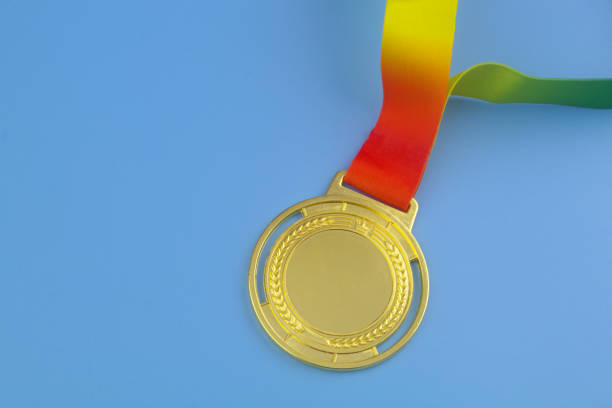 Gold medal with colorful ribbon on blue background, copy space for text.