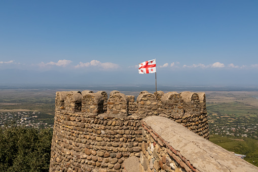 Ruined tower of Ujarma fortress with Georgian flag. Kakheti region, Georgia