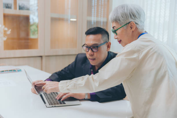 istock Two senior business person using computer laptop working discuss together at office 1371687806