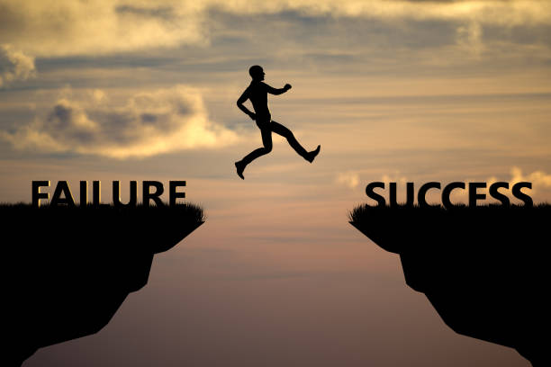 istock Silhouette man jumping on a cliff from failure to success with sunset sky background 1371690082