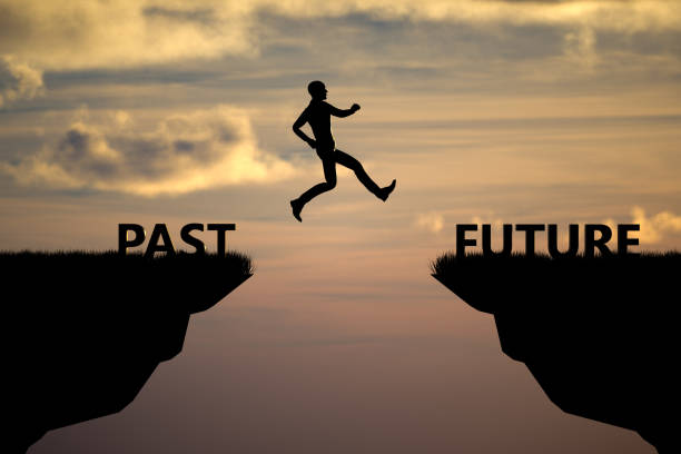 istock Silhouette man jumping on a cliff from past to future with sunset sky background 1371690119
