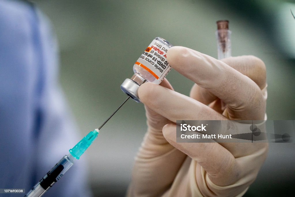Pfizer-BioNTech COVID-19 vaccine doses Pfizer-BioNTech COVID-19 vaccine (Comirnaty) doses being prepared by gloved medical worker with syringe Vaccination Stock Photo