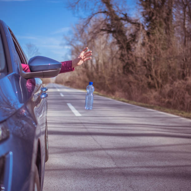 istock Blue car driver throwing away plastic waste from the car 1371693904