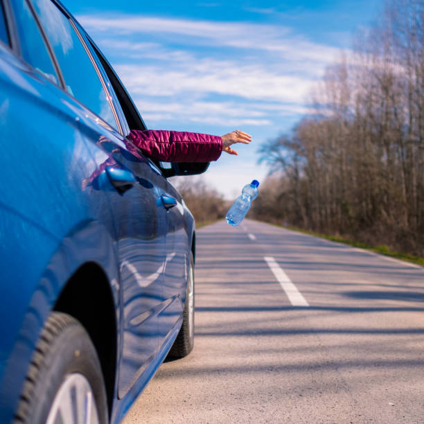 istock Blue car driver throwing away plastic bottle from the car 1371694039