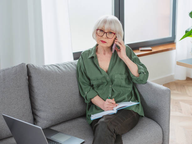 istock senior friendly woman entrepreneur work from home. Talking on the phone work with lap top. Business, self employed, senior woman concept 1371695270