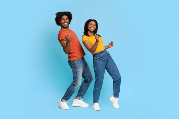 pareja afroamericana positiva posando en azul, bailando - couple young women casual excitement fotografías e imágenes de stock