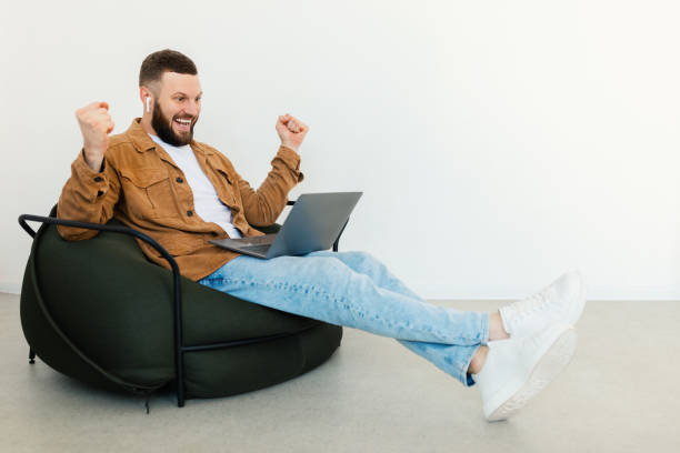 istock Joyful Freelancer Guy Using Laptop Computer Shaking Fists Sitting Indoor 1371700396