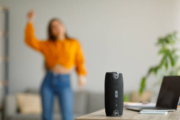 Young lady dancing to popular music at home, selective focus on portable wireless speaker, copy space