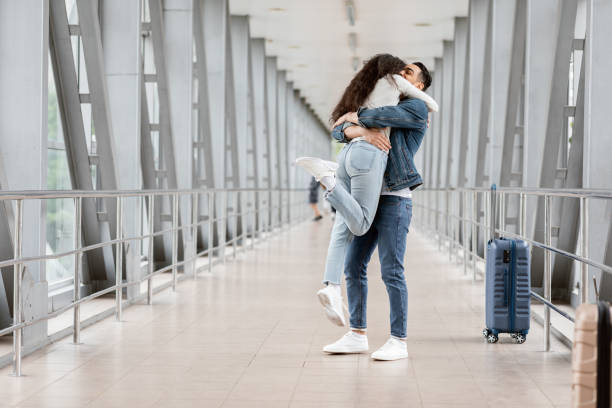 Long-Awaited Meeting. Romantic Young Arab Couple Embracing At Airport After Arrival Long-Awaited Meeting. Romantic Young Arab Couple Embracing At Airport After Arrival, Excited Middle Eastern Guy Lifting Up His Girlfriend In Air While Standing Together At Terminal Hallway airport hug stock pictures, royalty-free photos & images