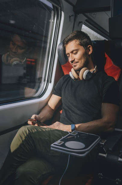 jeune homme voyageant en train - bus inside of people train photos et images de collection