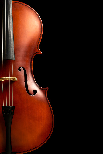 FRONT VIEW OF HALF OF A CELLO ON DARK BACKGROUND. COPY SPACE. CLASSICAL MUSIC CONCERT.
