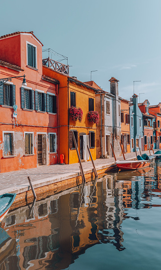 Colourful houses on the canal in famous travel destination Burano island and boats lining side canals with beautiful reflection in Burano, Venice, Italia