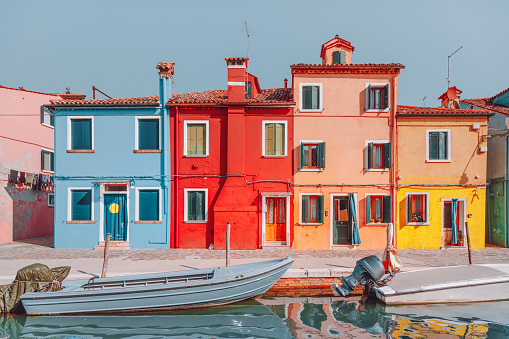 Colourful houses on the canal in famous travel destination Burano island and boats lining side canals with beautiful reflection in Burano, Venice, Italia