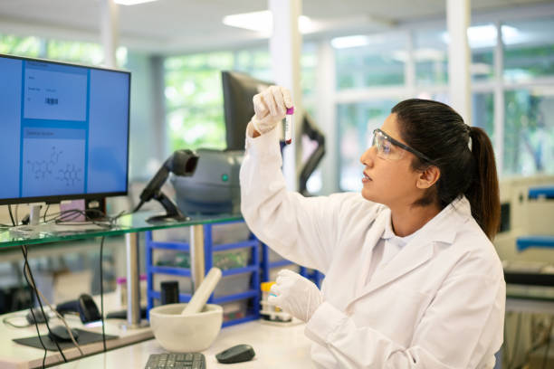 mulher cientista examinando amostra médica em tubo de ensaio em laboratório - blood sample blood tube pathologist - fotografias e filmes do acervo