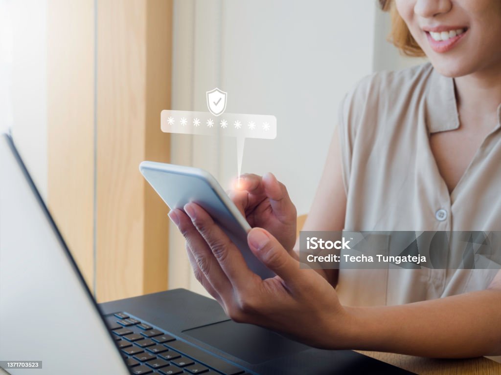 Two steps authentication concept. Virtual safety shield icon while access on phone with laptop for validate password, Identity verification, cybersecurity with biometrics authentication technology. Security Stock Photo