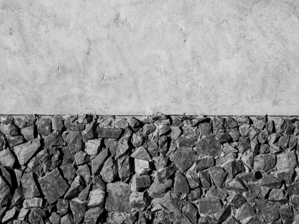 Strong wall decoration with many stones on concrete wall. Cement wall texture decorated with crack rocks, black and white style.