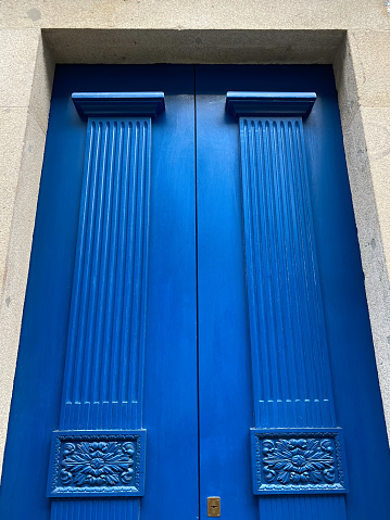 Low angle view of tall blue wooden entrance doorway, Viana do Castelo, Portugal. Street view. Winter day light.