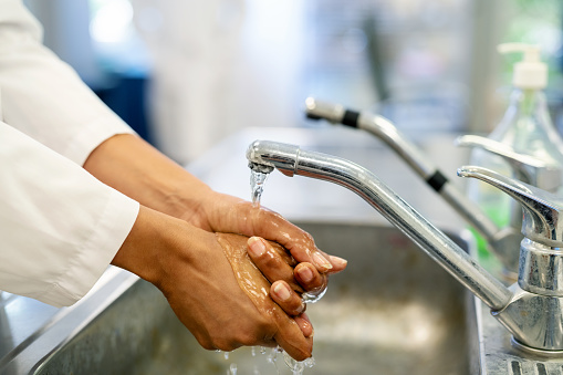 Close-up of a male scientist washing hands in the sink. Part of a doctor washing his hands at sink at science laboratory.
