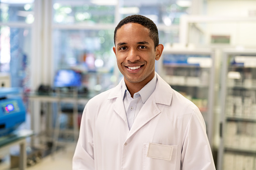 Portrait of a confident male scientist standing in a medical laboratory. Man wearing lab coat looking at camera and smiling.