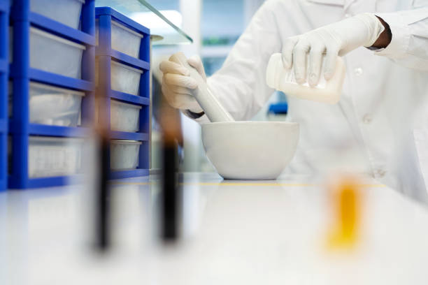 Close-up of a scientist making medicine in laboratory Midsection of a scientist making medicine in laboratory. Professional using mortar and pestle pouring solution from bottle. mortar and pestal stock pictures, royalty-free photos & images
