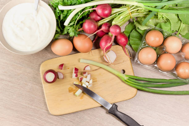 Fresh radish, egg, parsley, chives and sour cream for making salad on a wooden table close-up