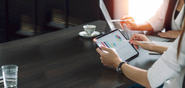Businesspeople working at office with tablet and document on his desk, doing planning analyzing the financial report, business plan investment, finance analysis concept. Economic business discussions.