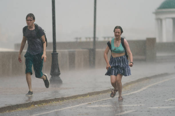 running from the rain people in summer day - rain drenched men wet imagens e fotografias de stock