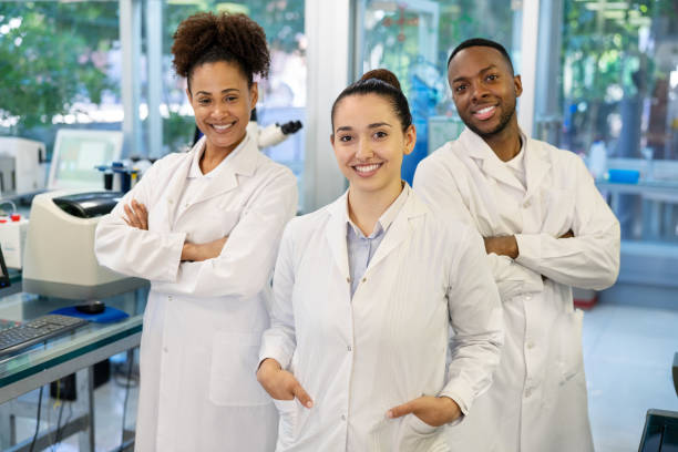 portrait de trois scientifiques réunis en laboratoire - scientist research group of people analyzing photos et images de collection