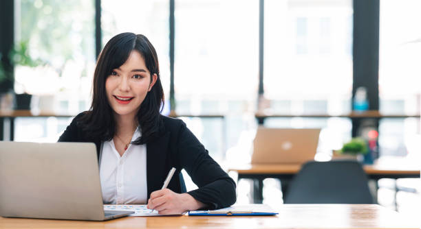 istock Confident asian businesswoman using laptop at work. Smiling and looking at camera. 1371708391