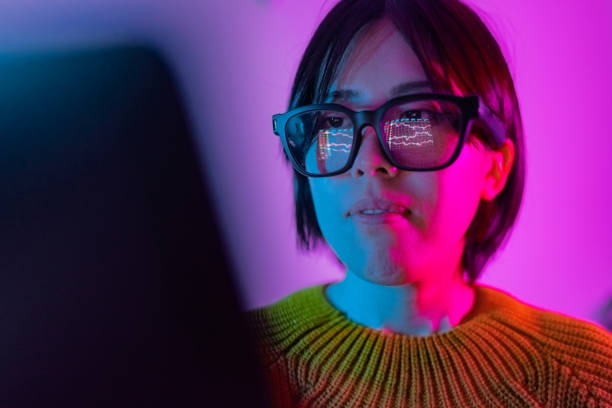 Woman checking chart for currency information on laptop. Cryptocurrency chart reflected on smart glasses.