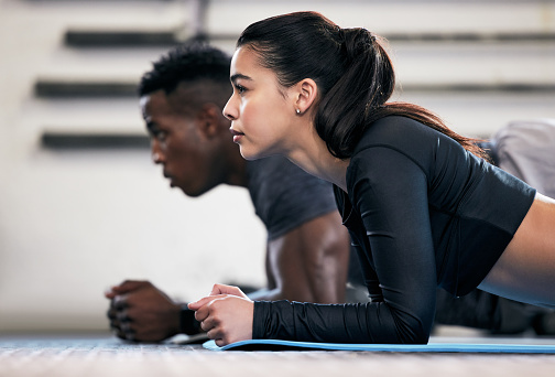 Foto de un hombre y una mujer jóvenes haciendo ejercicios de tablón en un gimnasio photo
