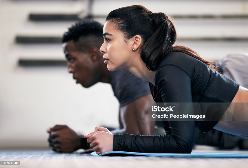 Shot of a young man and woman doing plank exercises in a gym Where strong bodies begin Exercise Class Stock Photo
