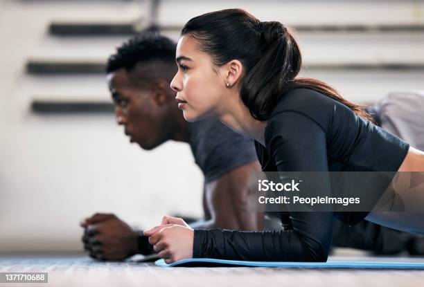 Shot Of A Young Man And Woman Doing Plank Exercises In A Gym Stock Photo - Download Image Now