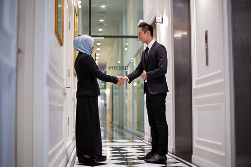 Two business people handshake for cooperation at office corridor