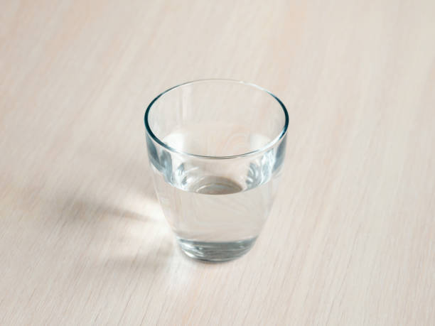 木製テーブルにミネラルウォーターのグラス。テーブルの上のボトルから精製された新鮮な飲み物の水を閉じます。 - purified water bottle water drink ストックフォトと画像