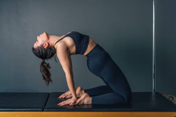 young woman doing pilates and yoga exercise on pilates machine - concentration flexibility full length healthy lifestyle imagens e fotografias de stock