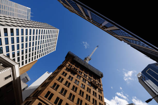 Low angle view of old and new tall buildings. A crane is on top of the older building.
