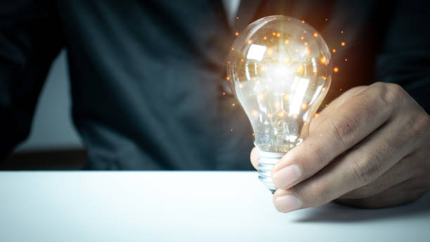 istock businessman hand holding light bulb with finance document and tool. 1371714472