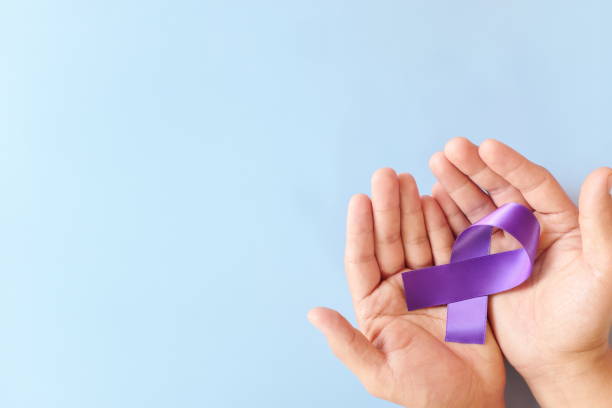 Top view of male hands holding purple ribbon color. Testicular, pancreatic cancer, epilepsy, leiomyosarcoma, lupus, Alzheimer's disease, Hodgkin lymphoma and cystic fibrosis awareness concept. vista superior de las manos masculinas sosteniendo el color púrpura de la cinta. testicular, cáncer de páncreas, epilepsia, leiomiosarcoma, lupus, enfermedad de alzheimer, linfoma de hodgkin y concepto de conciencia de fibrosis quística.